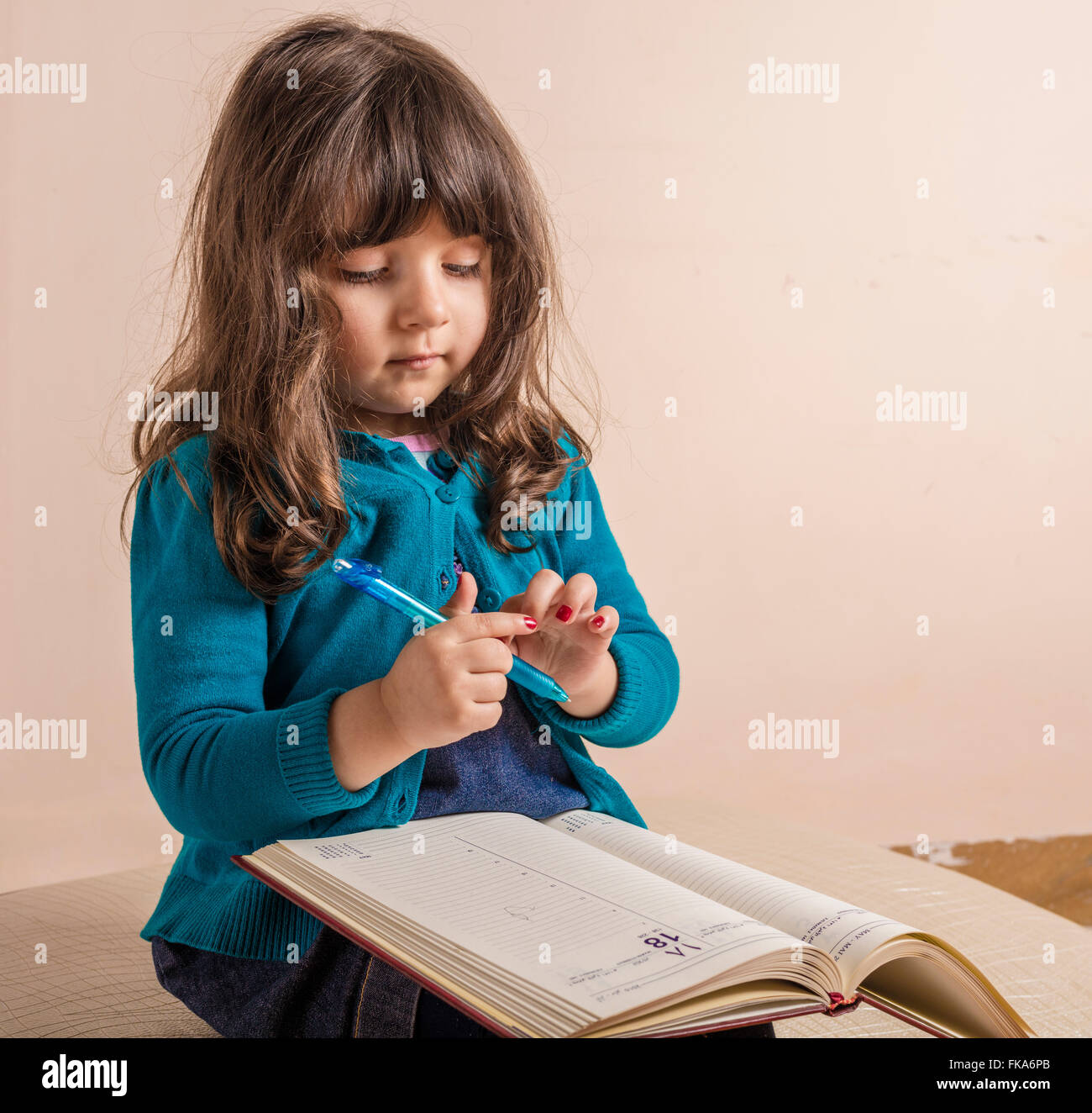 Samll girl inside studio with red copybook in hand Stock Photo