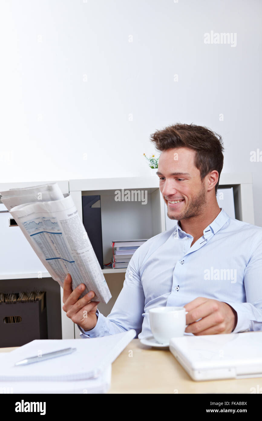 Young business man in office reading the appointments section in newspaper Stock Photo