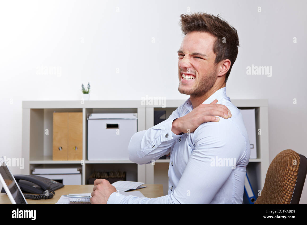 Business man with shoulder pain in office at desk Stock Photo Alamy