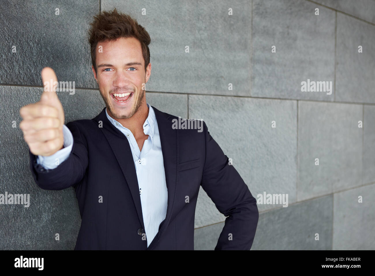 Happy business man in urban city holding thumbs up Stock Photo