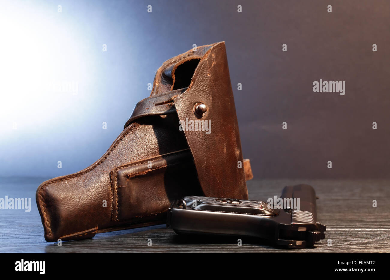 Old leather handgun holster and pistol on dark background Stock Photo