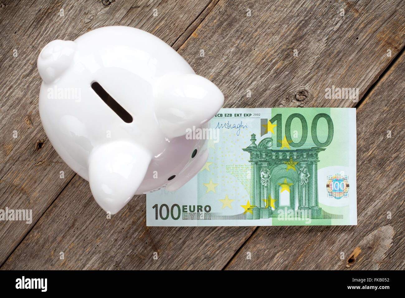 White Piggy Bank With 100 Euro On Wooden Surface Top View Stock