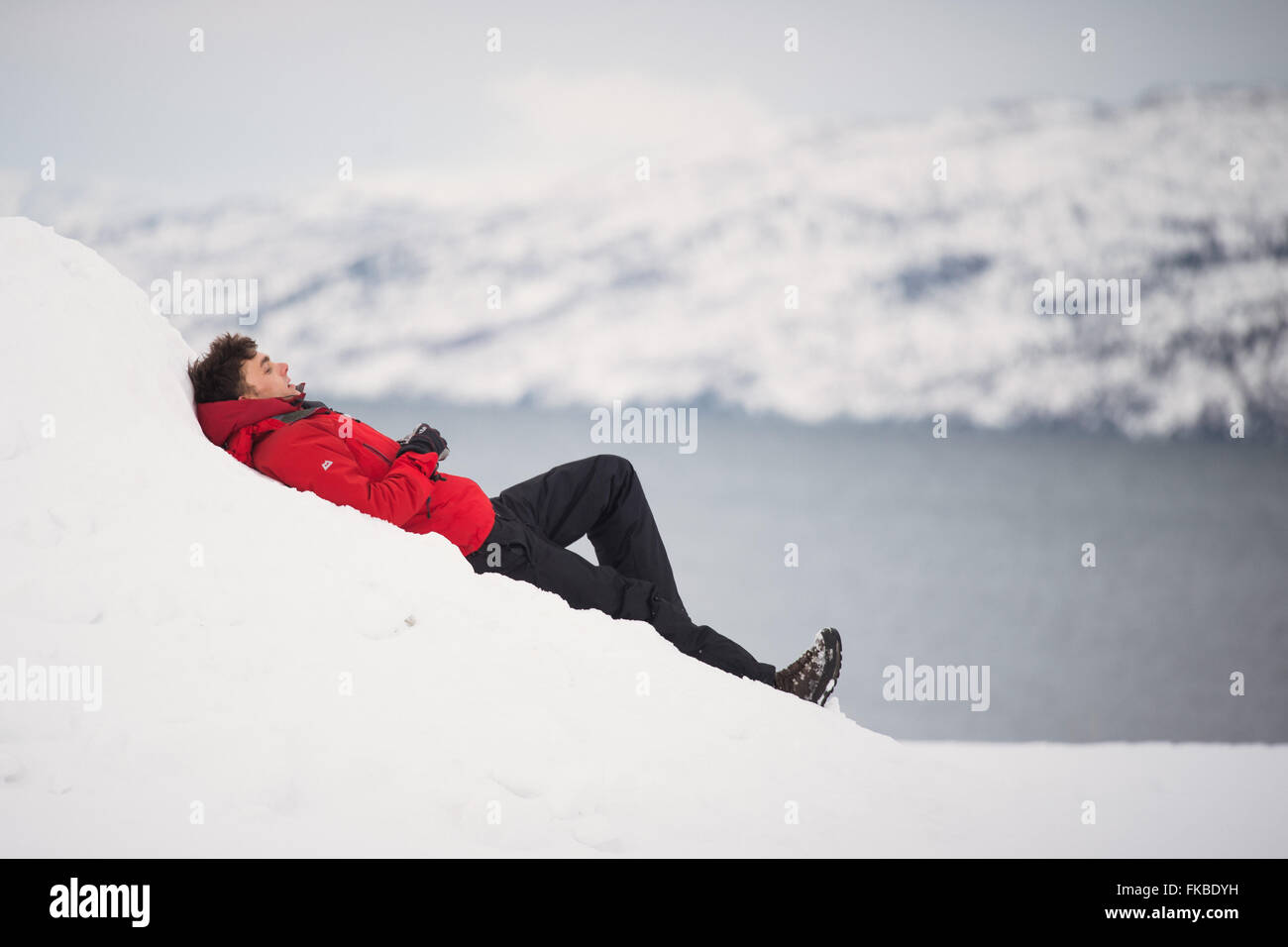 A Man In A Red Jacket Lies On A Bank Of Snow In Alta In Finnmark