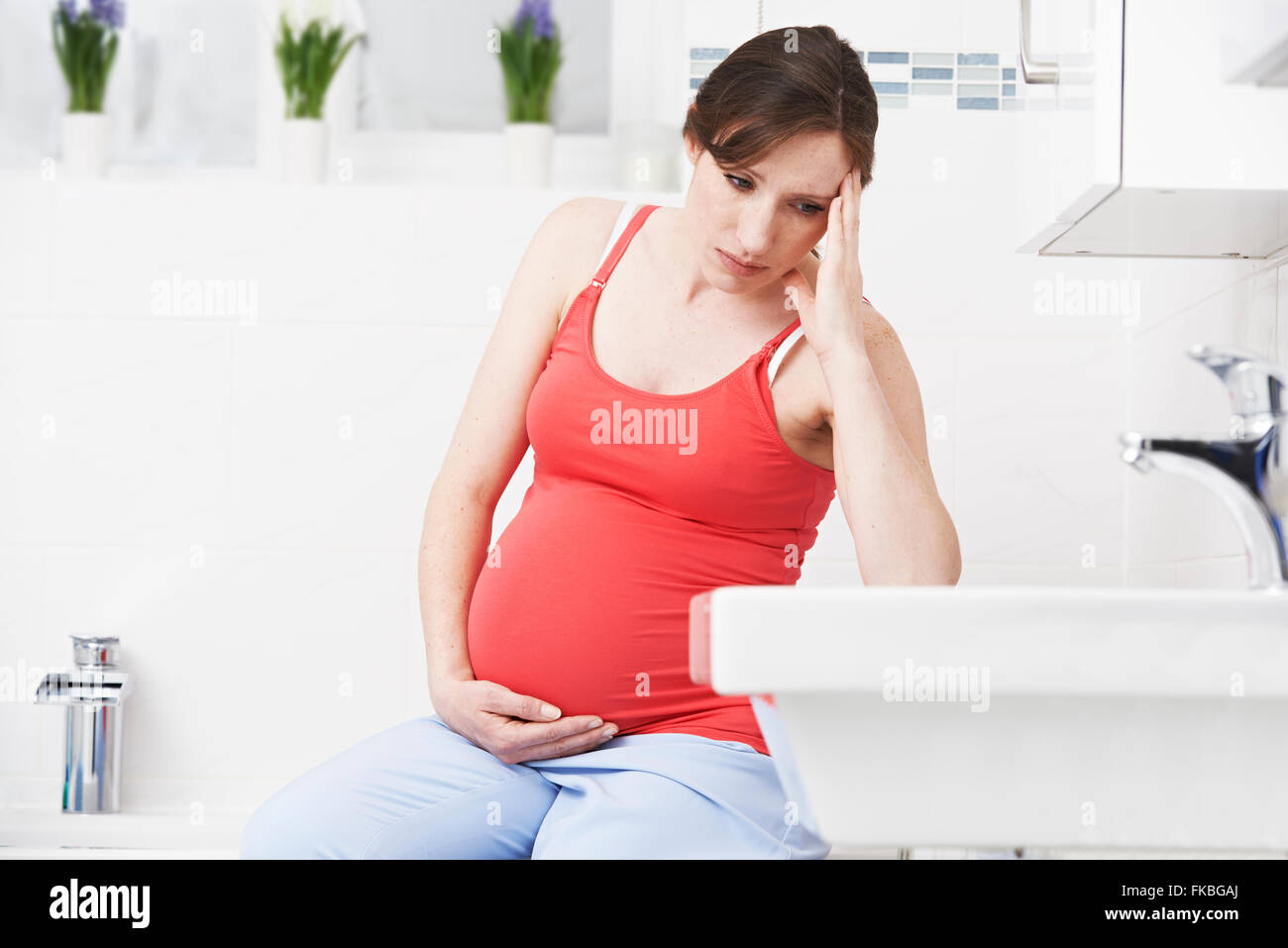 Pregnant Woman Suffering With Morning Sickness In Bathroom Stock Photo