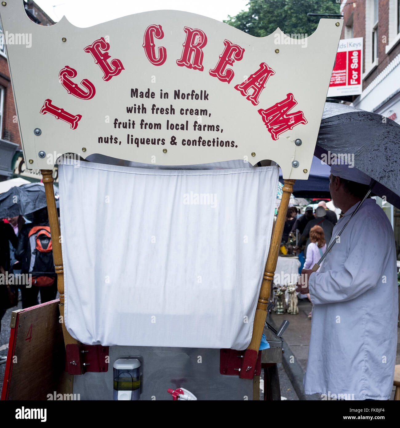 Ice cream man sheltering under a umbrella from the rain Stock Photo Alamy