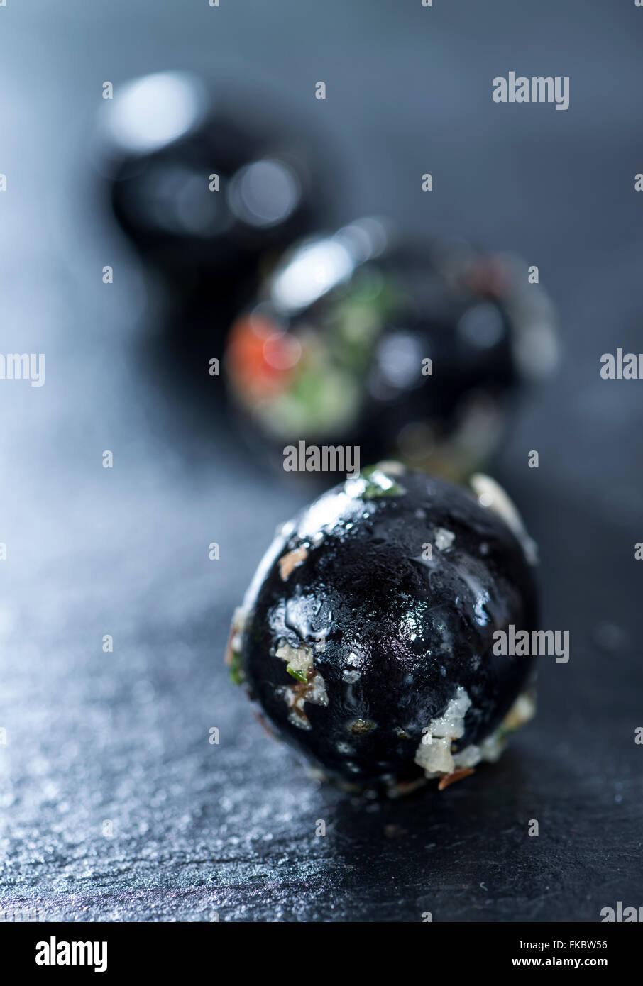 Portion of pickled black Olives with garlic and fresh herbs (close-up shot) Stock Photo