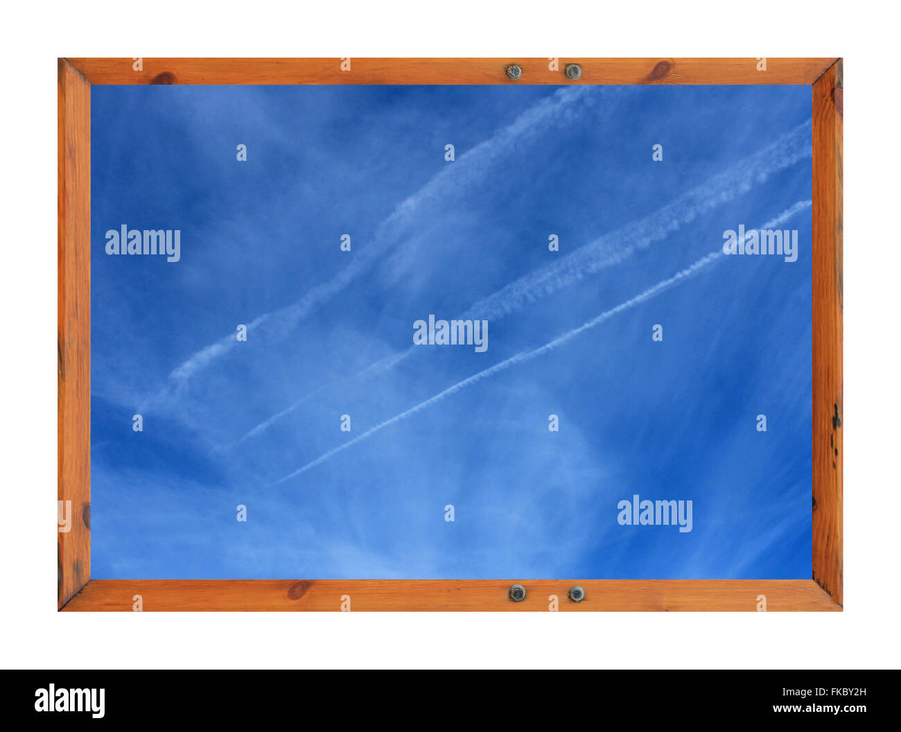 Scenic view of white vapor trails in blue sky surrounded by a wooden picture frame. Stock Photo