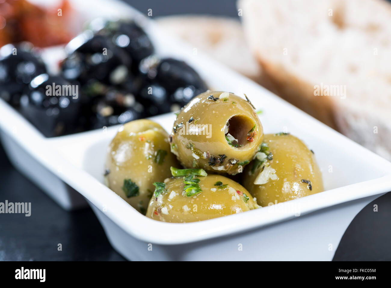Mixed Olives (black and green ones) marinated with garlic and fresh Mediterranean herbs Stock Photo