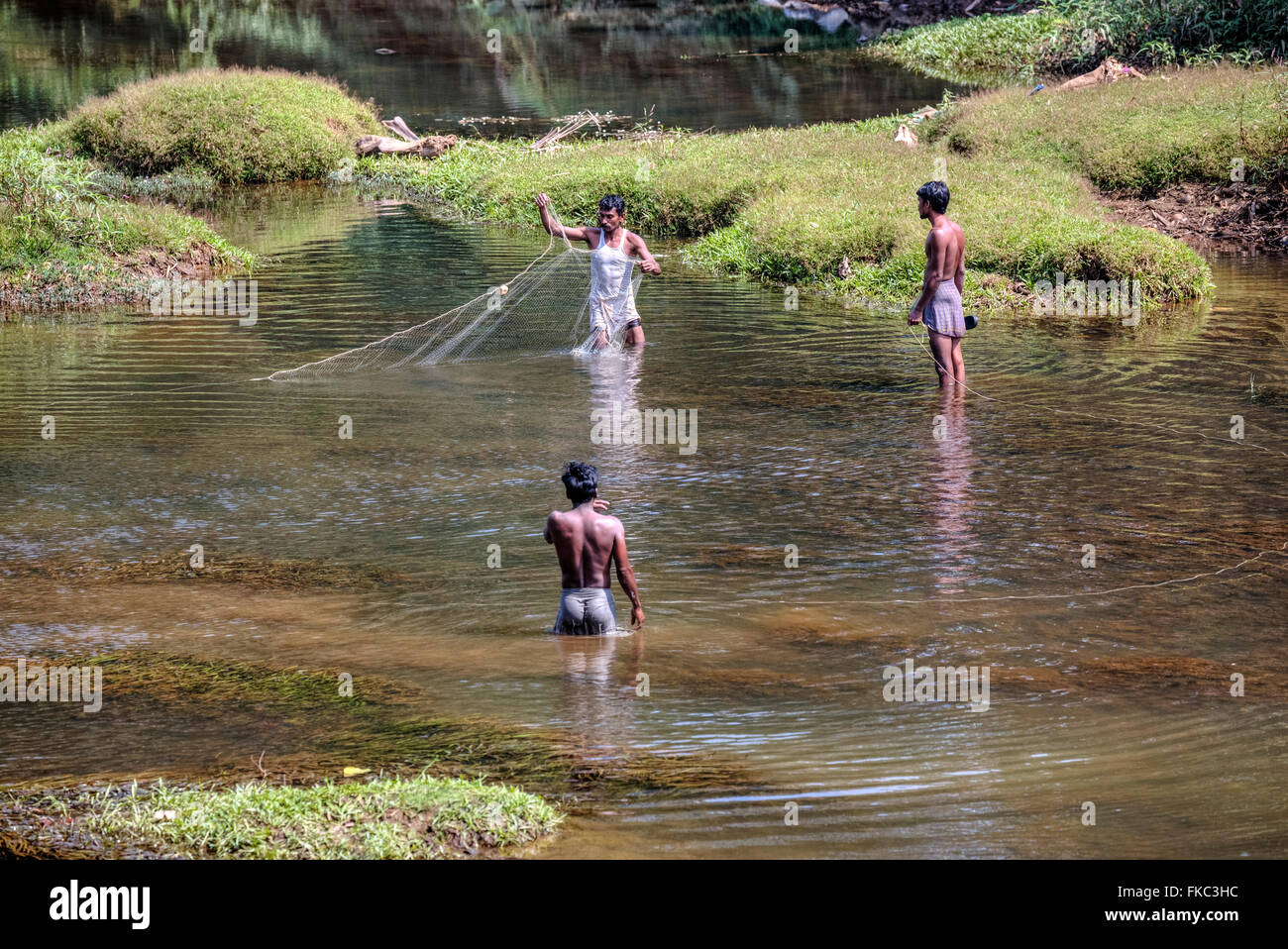 men fishing with a net in a river in Kerala, South India Stock Photo