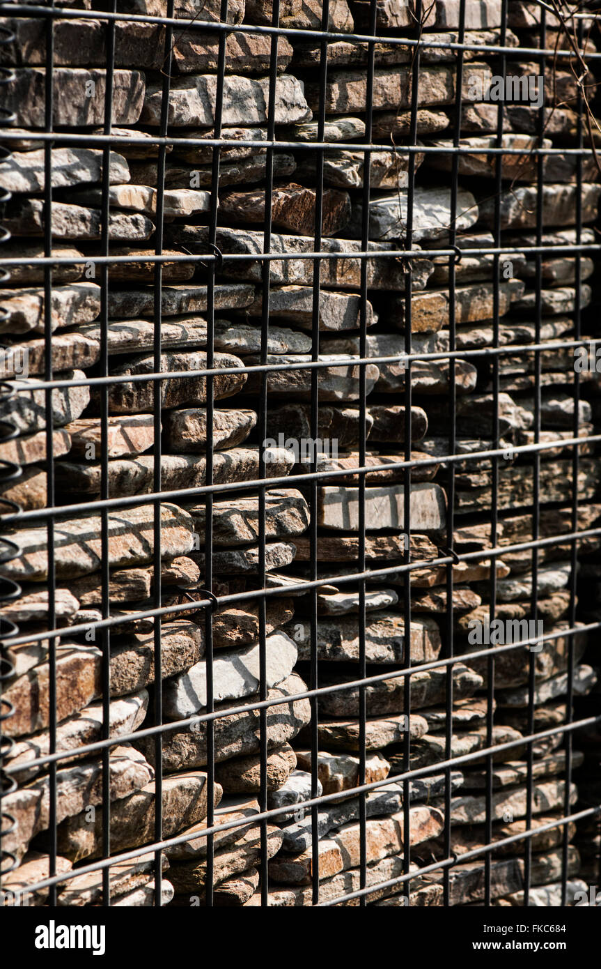 Portrait image of a small section of stone wall held in place by wire fencing/cage. Stock Photo