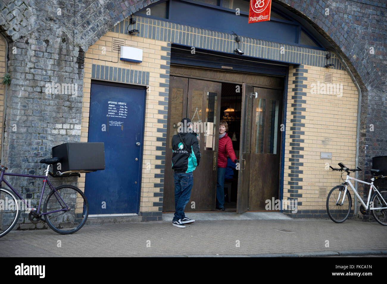 London. Hackney. Deliveroo collection from Patty Bun restaurant, in an old railway arch, Mentmore Terrace. Stock Photo