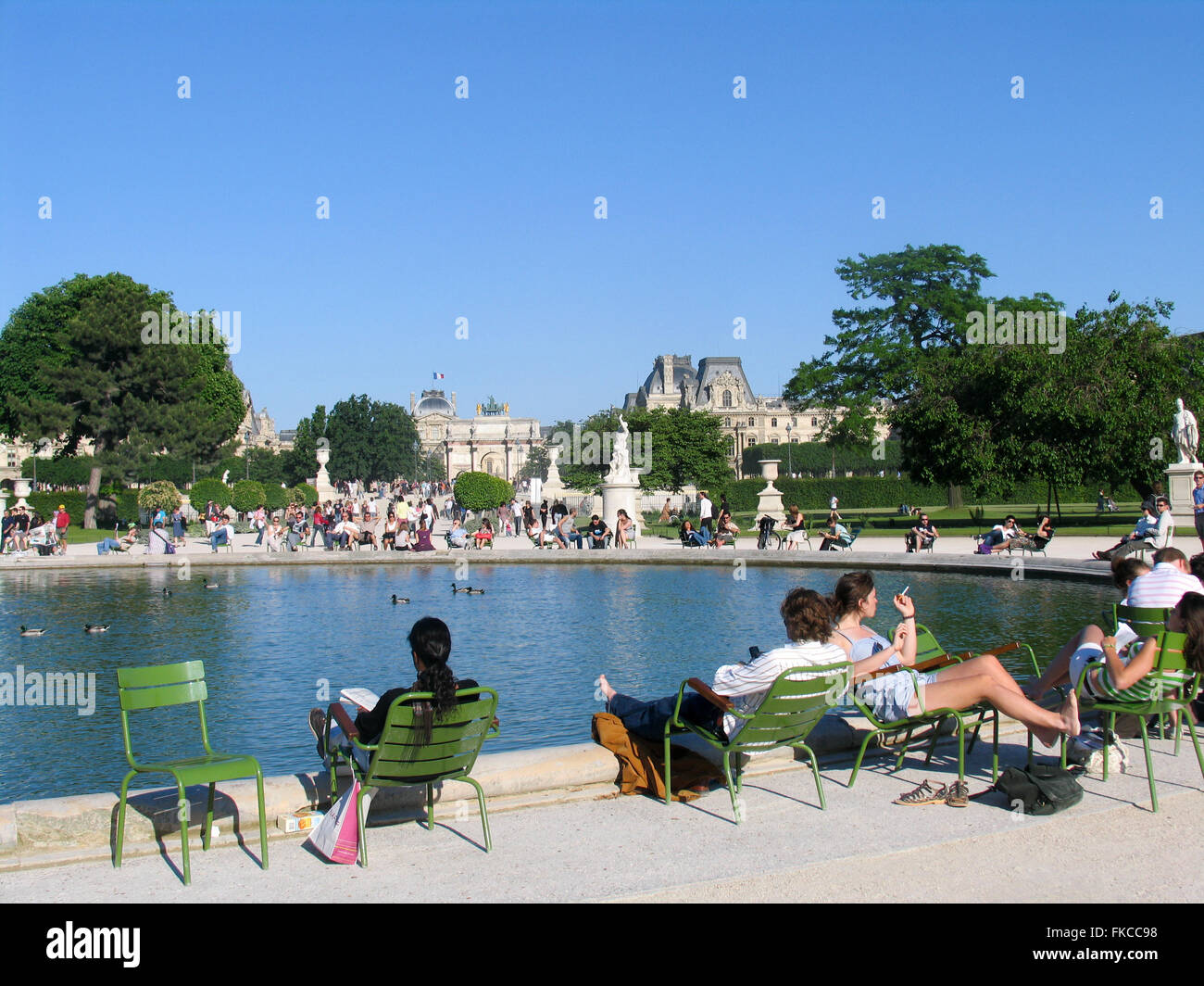 People sitting on green chairs  around The Grand Bassin Rond, Tuileries Garden, Paris. Stock Photo