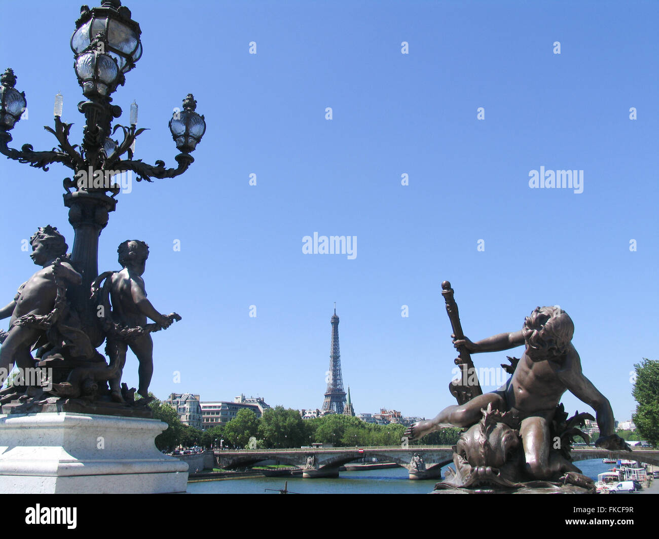 Bronze sculptures of cherubs on Pont Alexandre III, with the Eiffel Tower and Pont des Invalides. Stock Photo