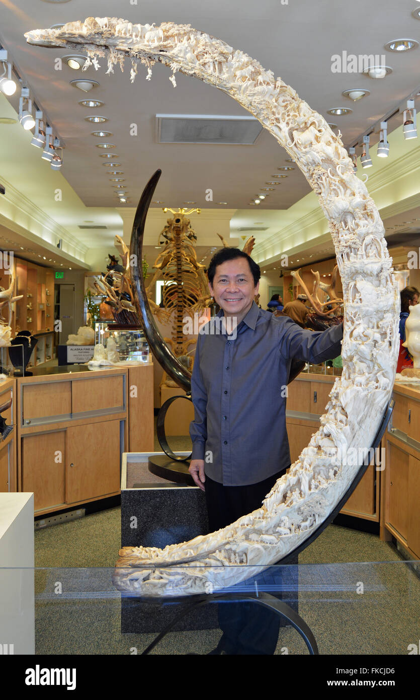 Master Sculptor Eddie Lee poses with his mammoth tusk carving that took 4 years to complete. Stock Photo