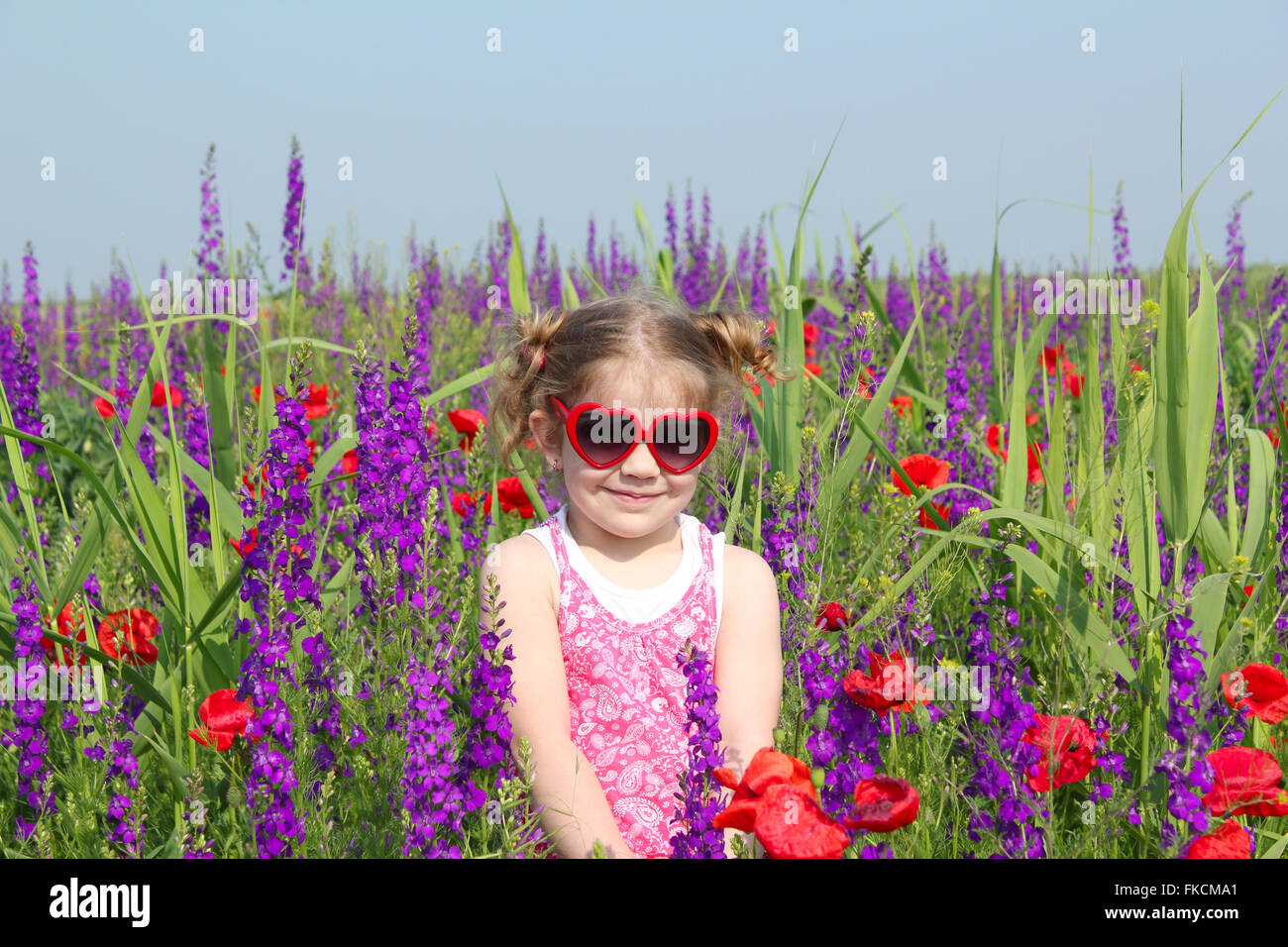 little girl standing in meadow with colorful flowers Stock Photo - Alamy