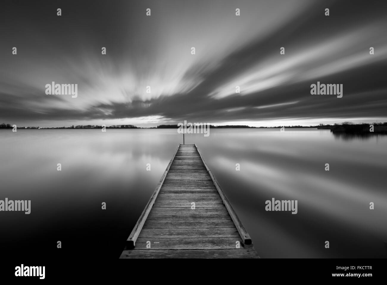 A small jetty on a lake near Amsterdam The Netherlands in black and white. A slow shutter speed was used to see the movement of Stock Photo