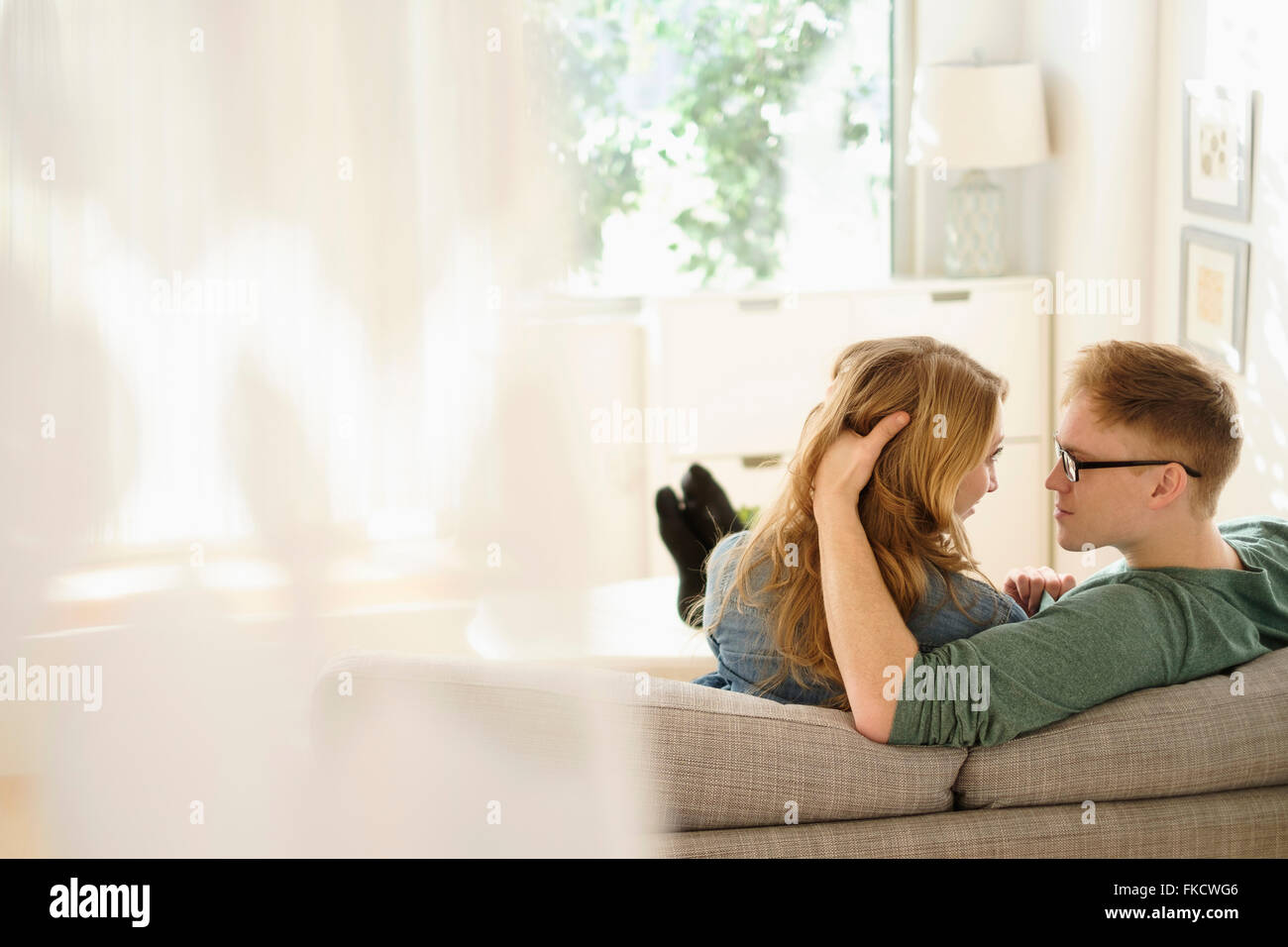 Young couple sitting face to face on sofa Stock Photo