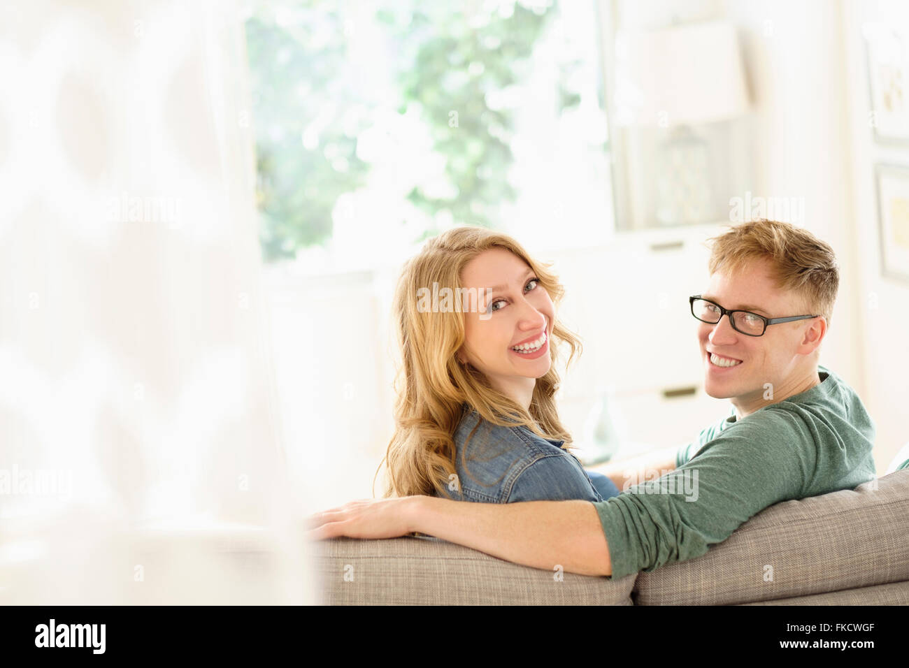 Portrait of young couple sitting on sofa Stock Photo - Alamy
