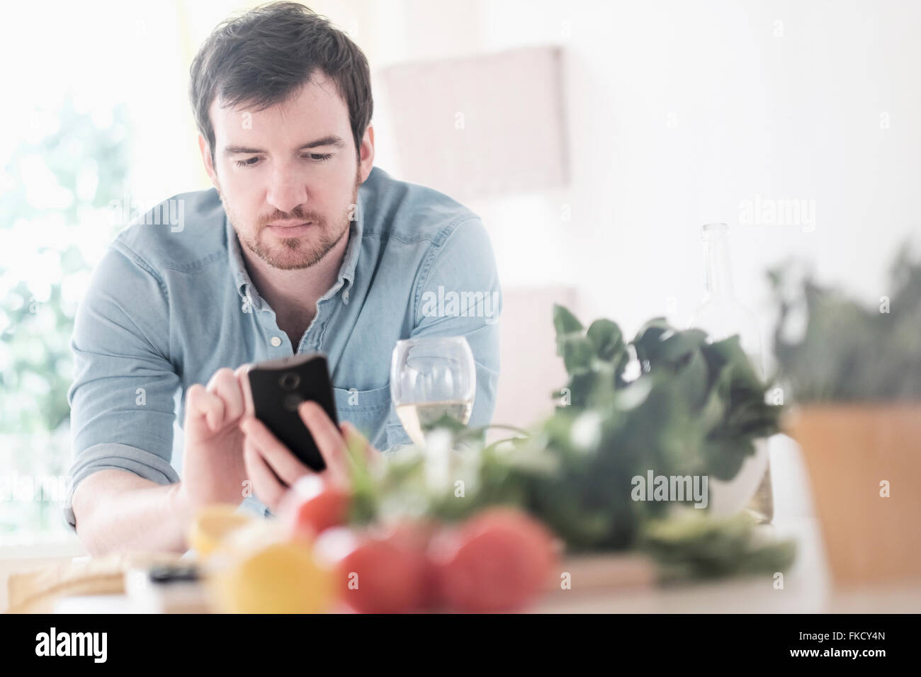 Man using phone in kitchen Stock Photo
