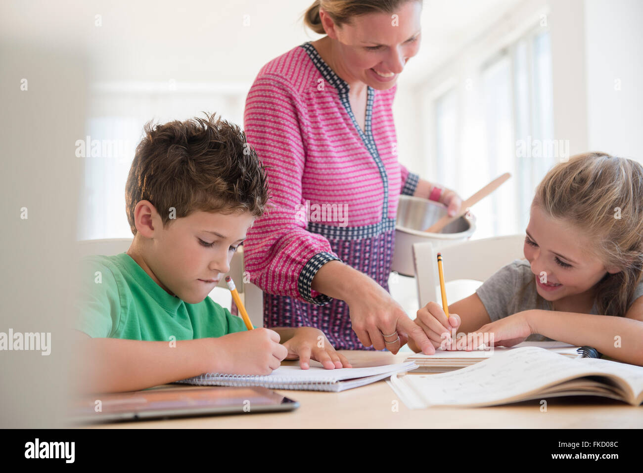 Mother assisting children (6-7, 8-9) with homework Stock Photo