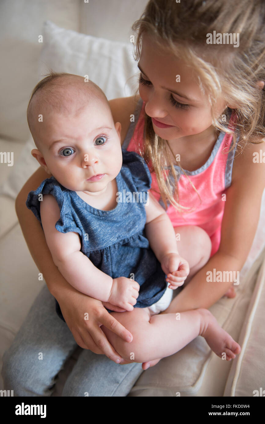 Young girl (6-7) holding baby sister (2-5 months) Stock Photo