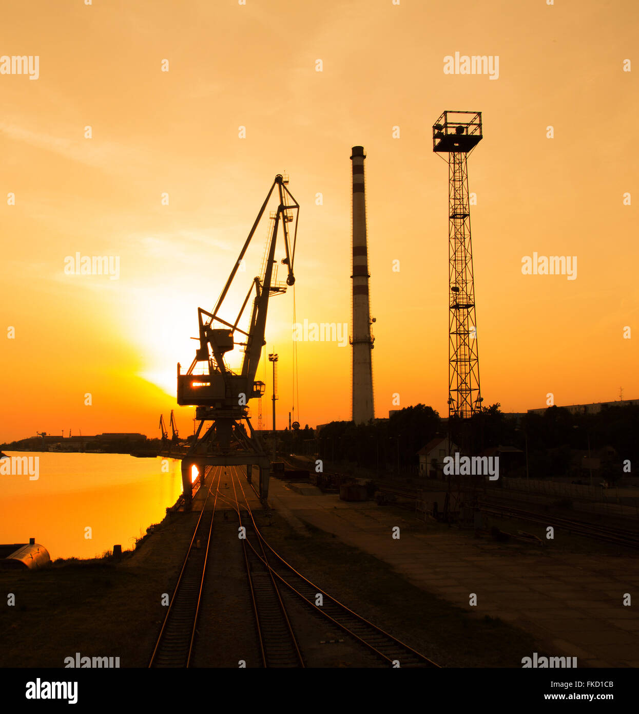 Portal crane in sunset with chimney and railroads Stock Photo