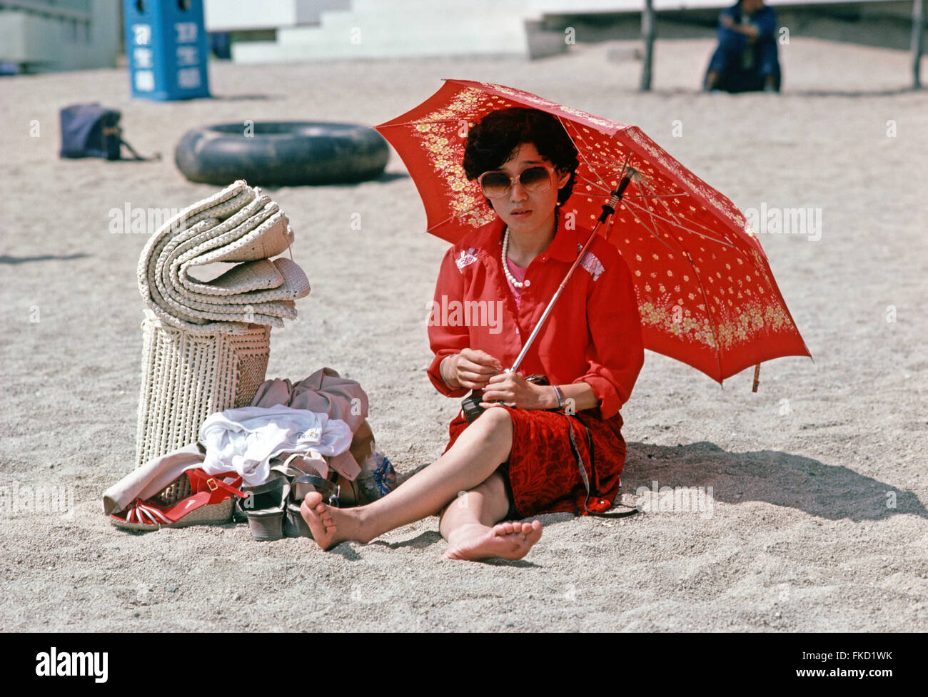 Chinese holiday makers under sun umbrellas on Qingdao beach, Sandong Province, China Stock Photo