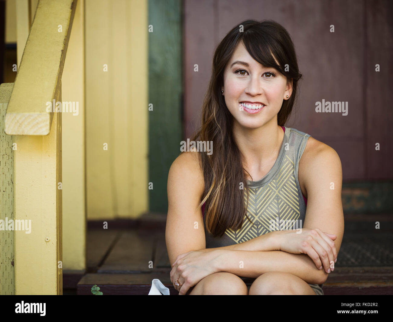 Portrait of young woman sitting on porch Stock Photo
