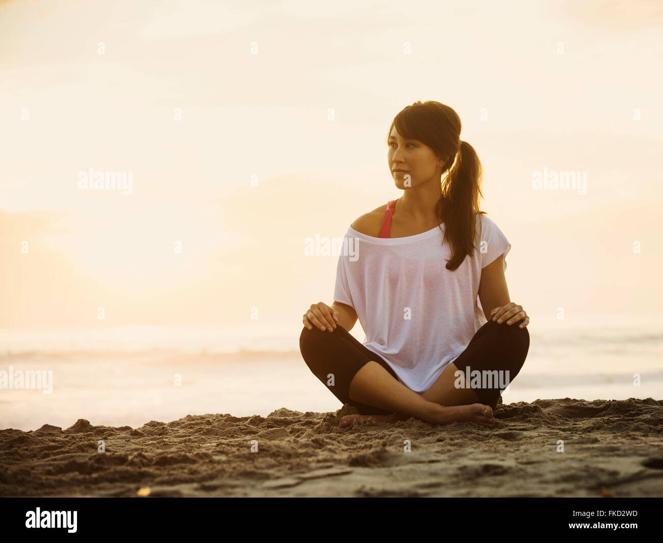 Young woman sitting on beach Stock Photo