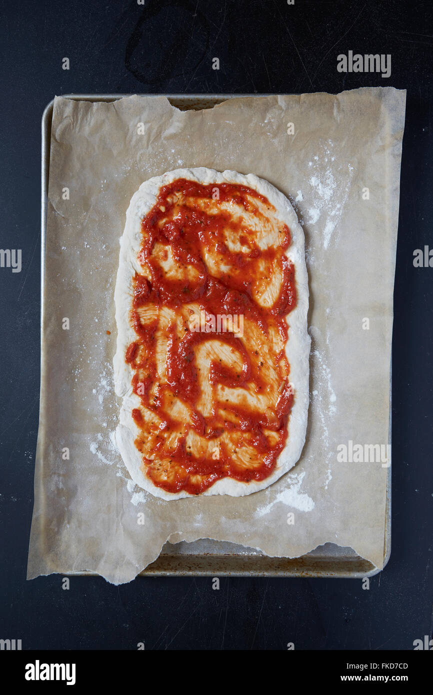 https://c8.alamy.com/comp/FKD7CD/pizza-dough-with-tomato-sauce-on-wax-paper-FKD7CD.jpg