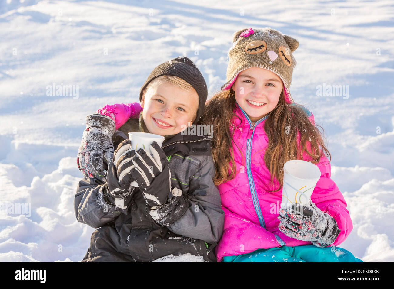 Boy (8-9) and girl (10-11) warming up drinking hot chocolate Stock Photo