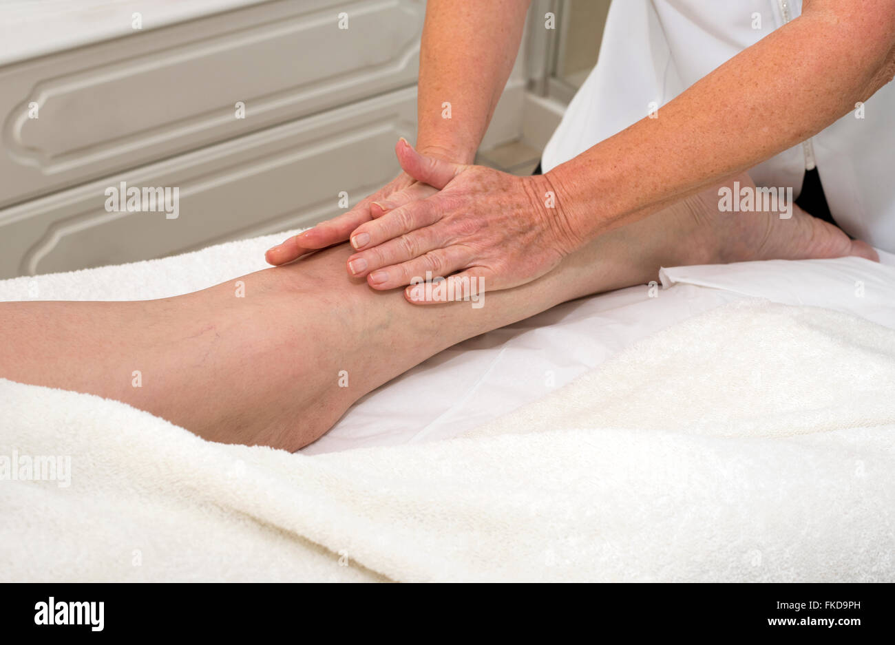 A masseuse massaging a woman client's leg massage Stock Photo