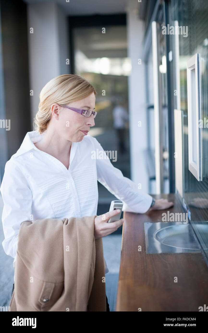 Businesswoman standing by ticket counter Stock Photo