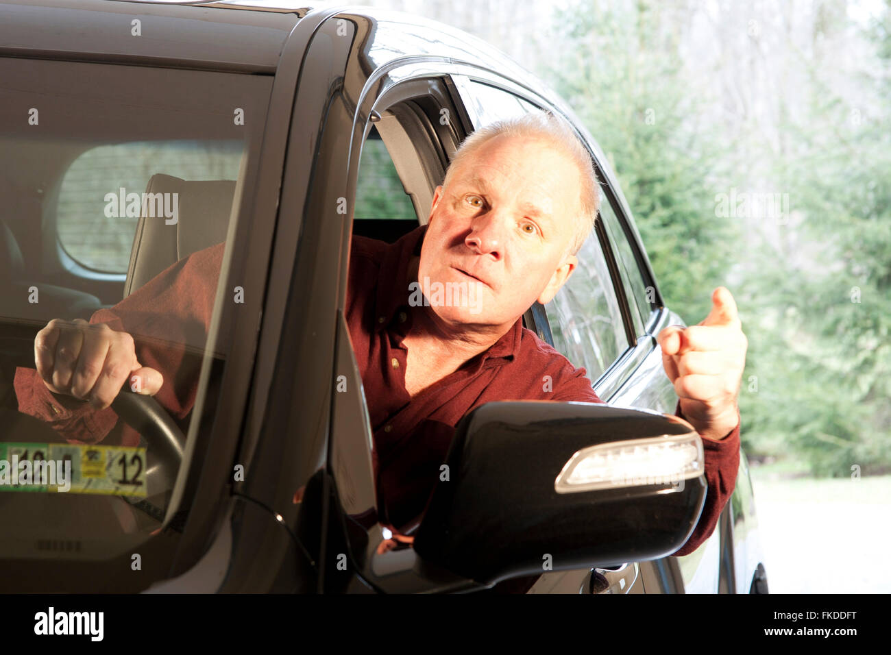Angry driver leaning out of window making threatening gestures Stock Photo