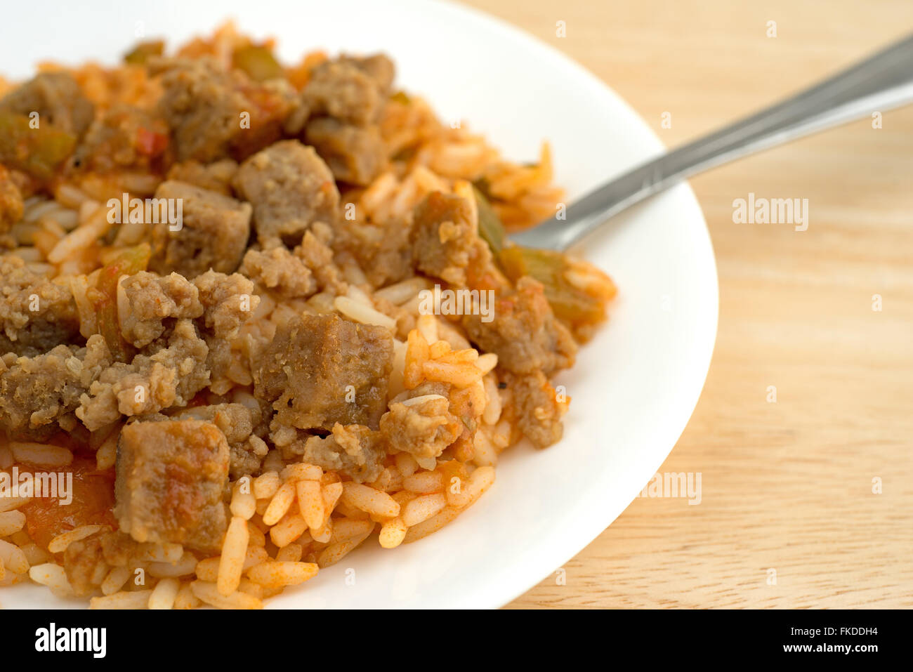 A serving of rice, green peppers and chunks of beef on a white plate ...