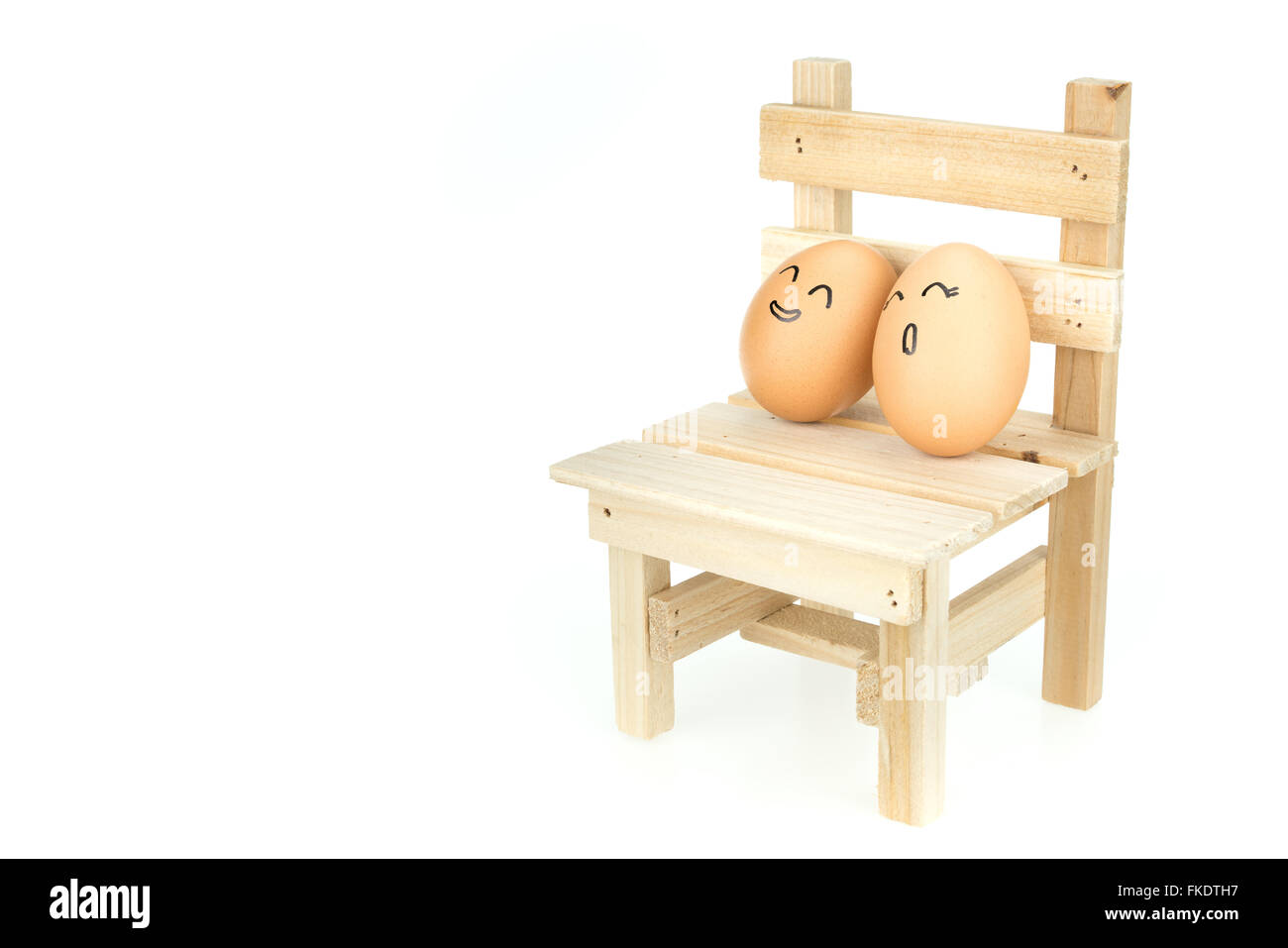 Lover eggs couple, lean on each other on wooden chair, isolated on white background Stock Photo