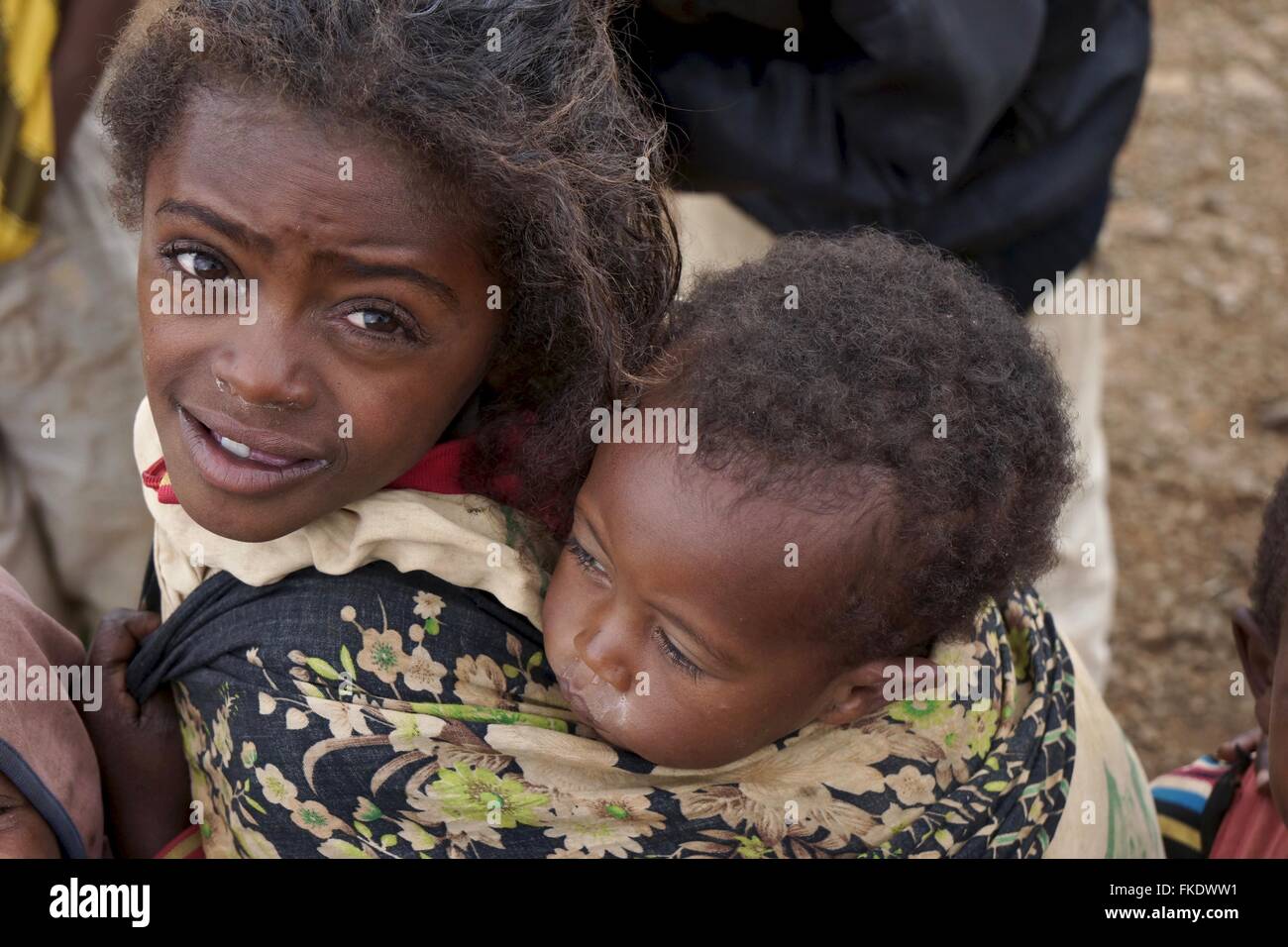A young Ethiopian girl carries her brother on her back at a market Stock Photo