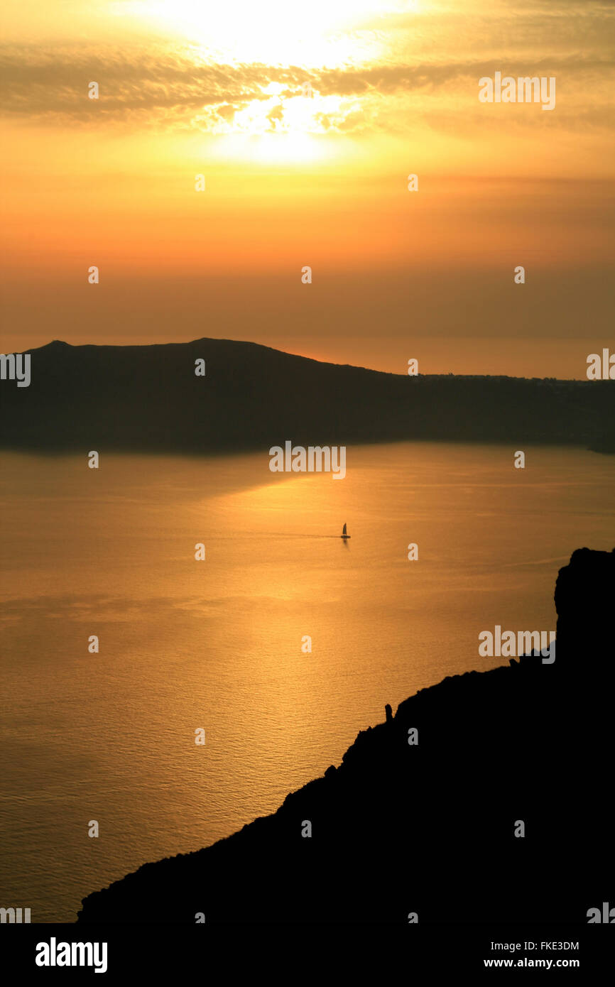 Santorini sun set over sea with lone distant sailboat, Cyclades islands in the Aegean Sea Stock Photo