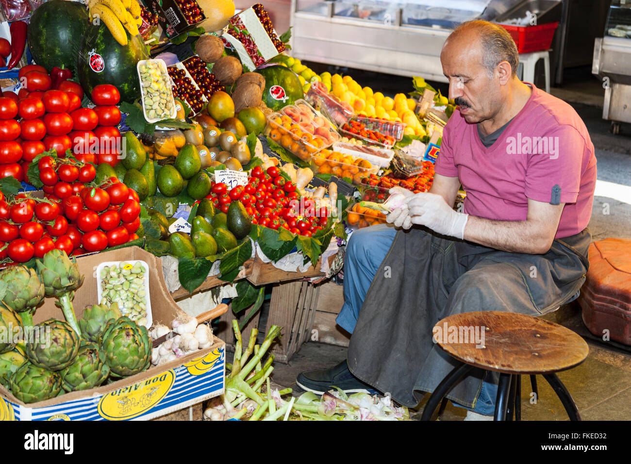 Stallholder sitting beside fruit and vegetable stall, Istanbul, Turkey Stock Photo
