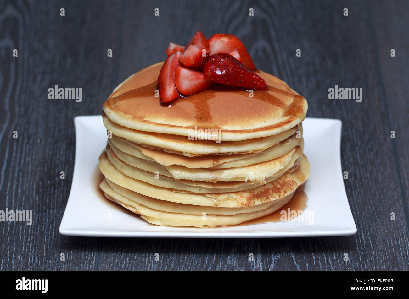 Stack of pancakes with strawberry on dark wooden background Stock Photo