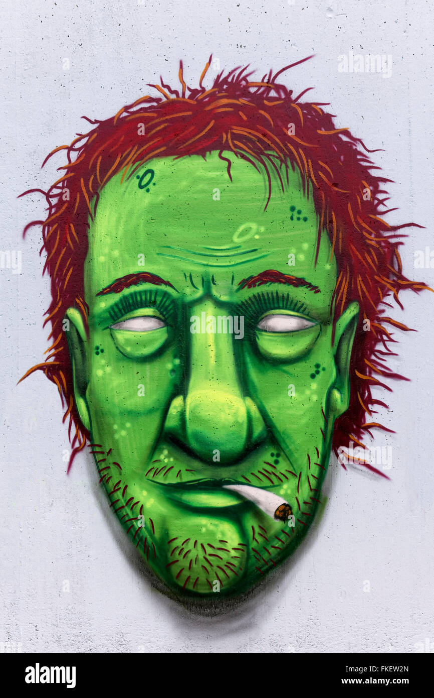 Portrait of a man with a green face smoking weed, hashish or marijuana joint, graffiti, street art, Düsseldorf Stock Photo