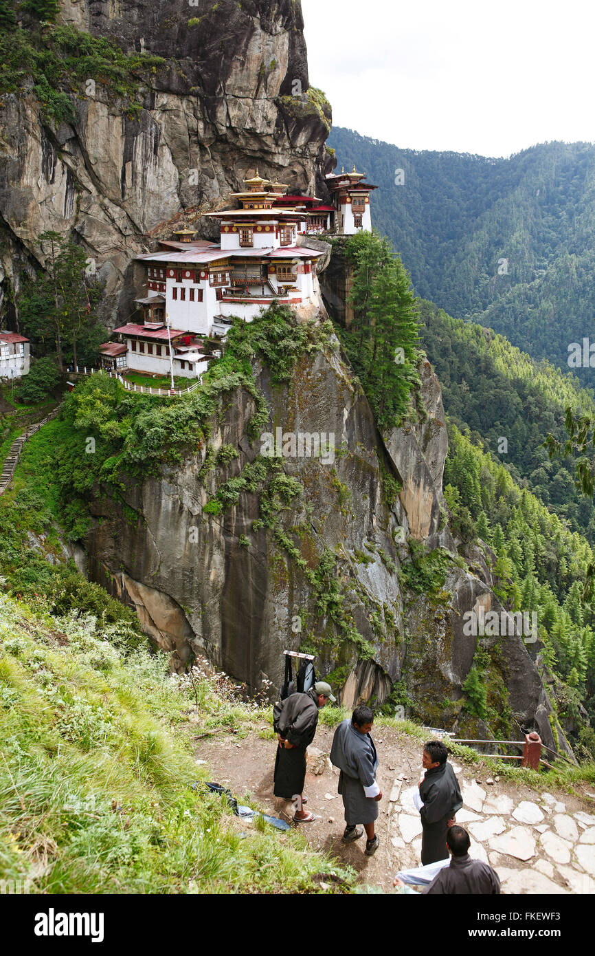 Tiger's Nest Monastery in the cliffside of Paro valley, men wearing traditional Gho dresses in the foreground Stock Photo