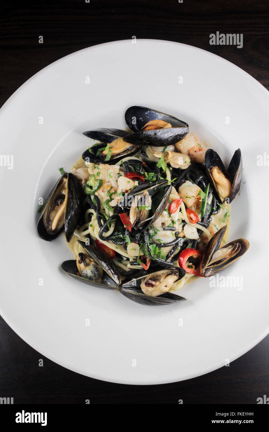 Squid ink pasta with mussels, shrimp and chiles Stock Photo Alamy