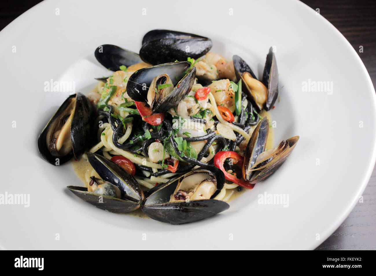Squid ink pasta with mussels, shrimp and chiles Stock Photo