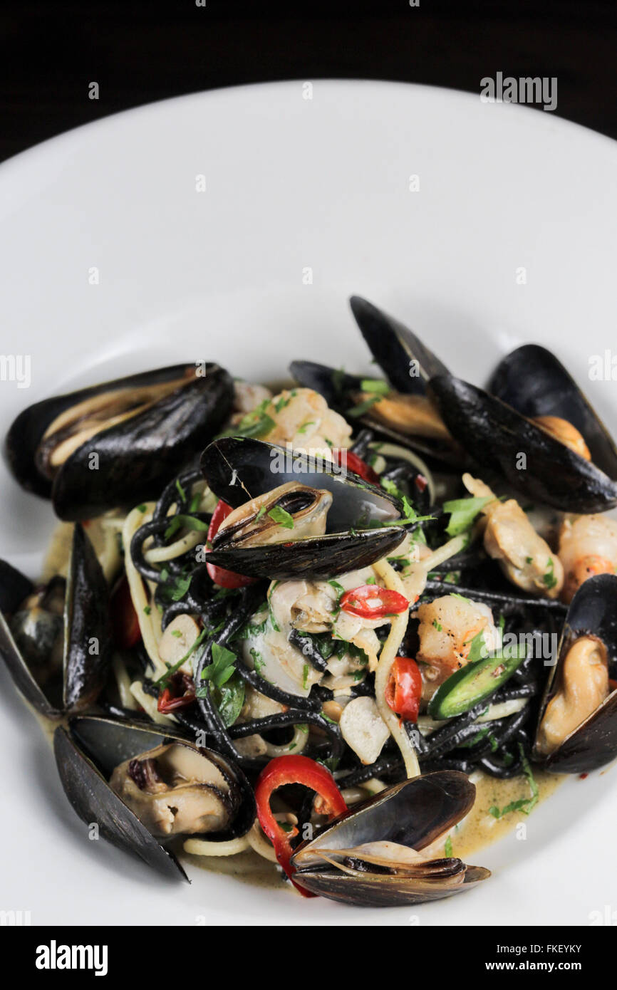 Squid ink pasta with mussels, shrimp and chiles Stock Photo