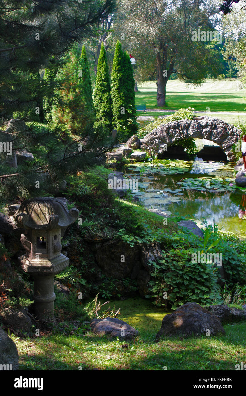 Canandaigua, New York, Sonnenberg Gardens and Mansion State Park. A Jananese lantern and stone arch bridge over a stream,. Stock Photo