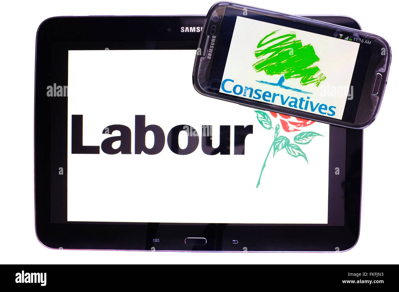A tablet with the Labour party logo on it by a smartphone with the Conservatives logo on it against a white background. Stock Photo