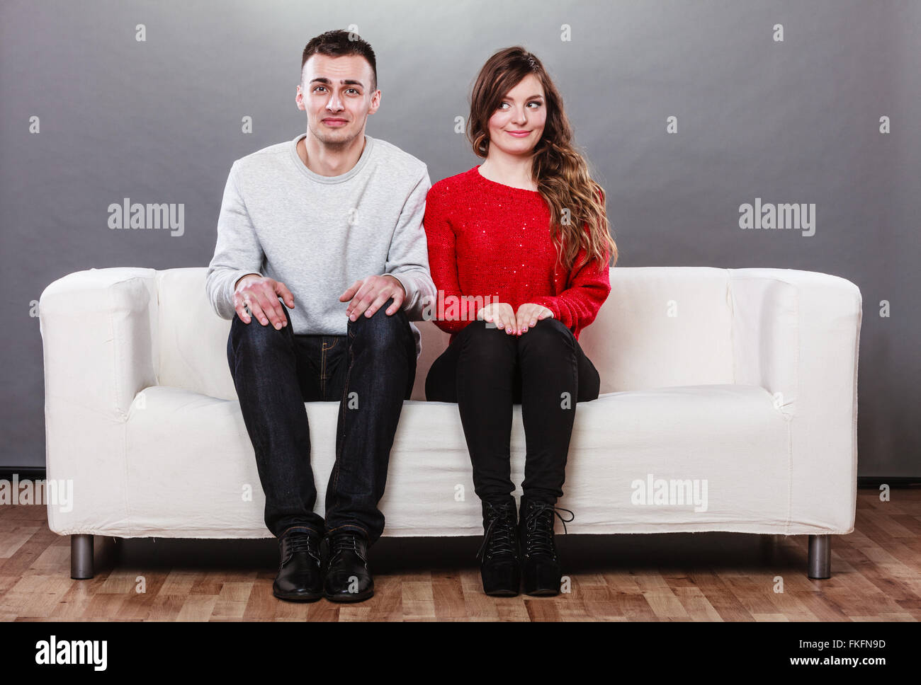 Shy woman and man sitting on sofa couch next to each other. First date