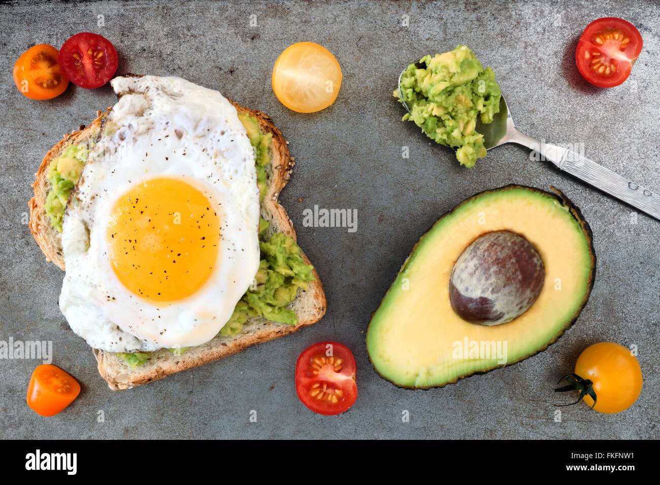 Open avocado, egg sandwich on whole grain bread with cherry tomatoes on