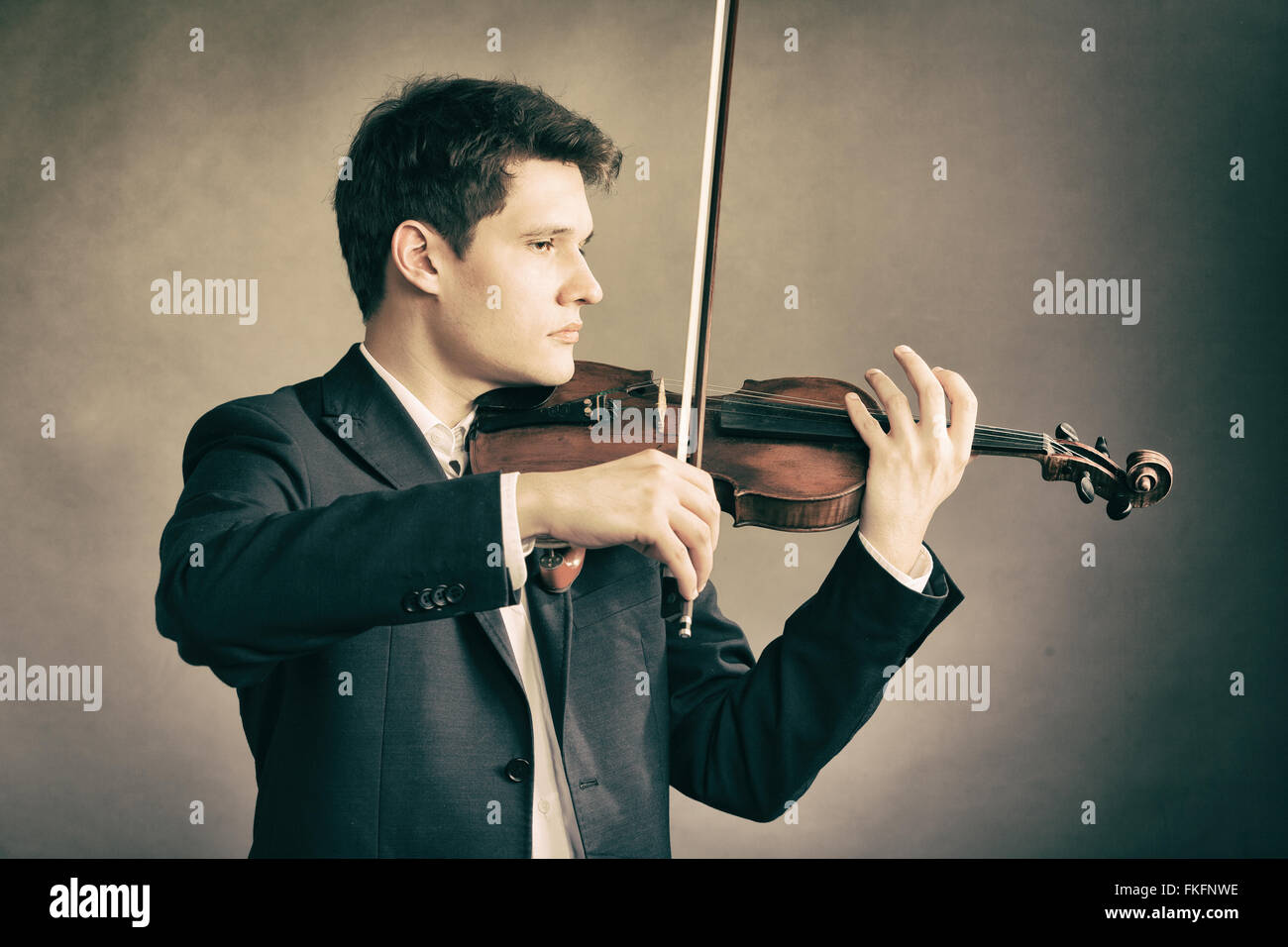Art and artist. Young elegant man violinist fiddler playing violin on brown. Classical music